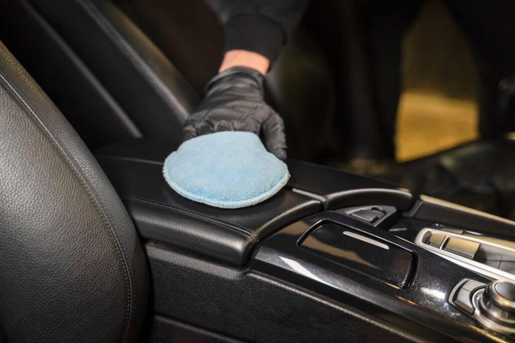 Man cleans leather armrest of car. Professional detailing